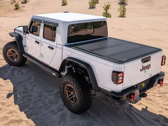 Lifestyle image of the RealTruck BAKFlip MX4 Hard Folding Tonneau Cover installed on a Jeep Gladiator