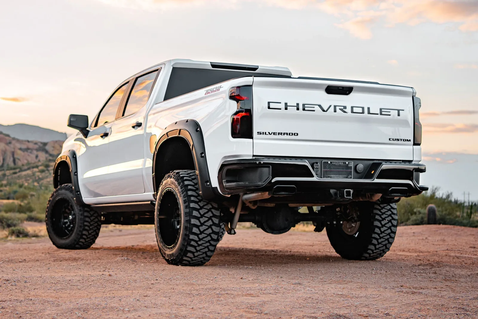 A white Chevy Silverado with Rough Country Pocket Fender Flares on a dirt road
