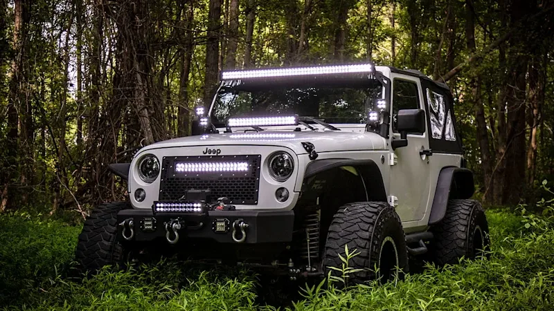 A Jeep off-roading in the woods with Rough Country LED lighting