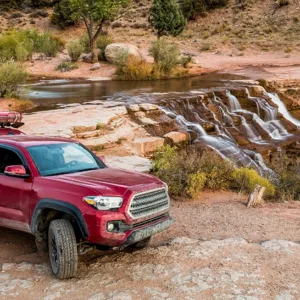 A red pickup truck with a camper shell next to a waterfall, showing the concept of payload capacity