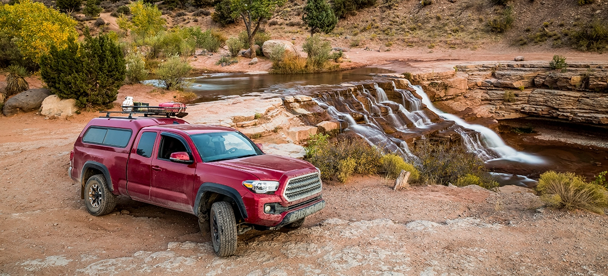 A red pickup truck with a camper shell next to a waterfall, showing the concept of payload capacity