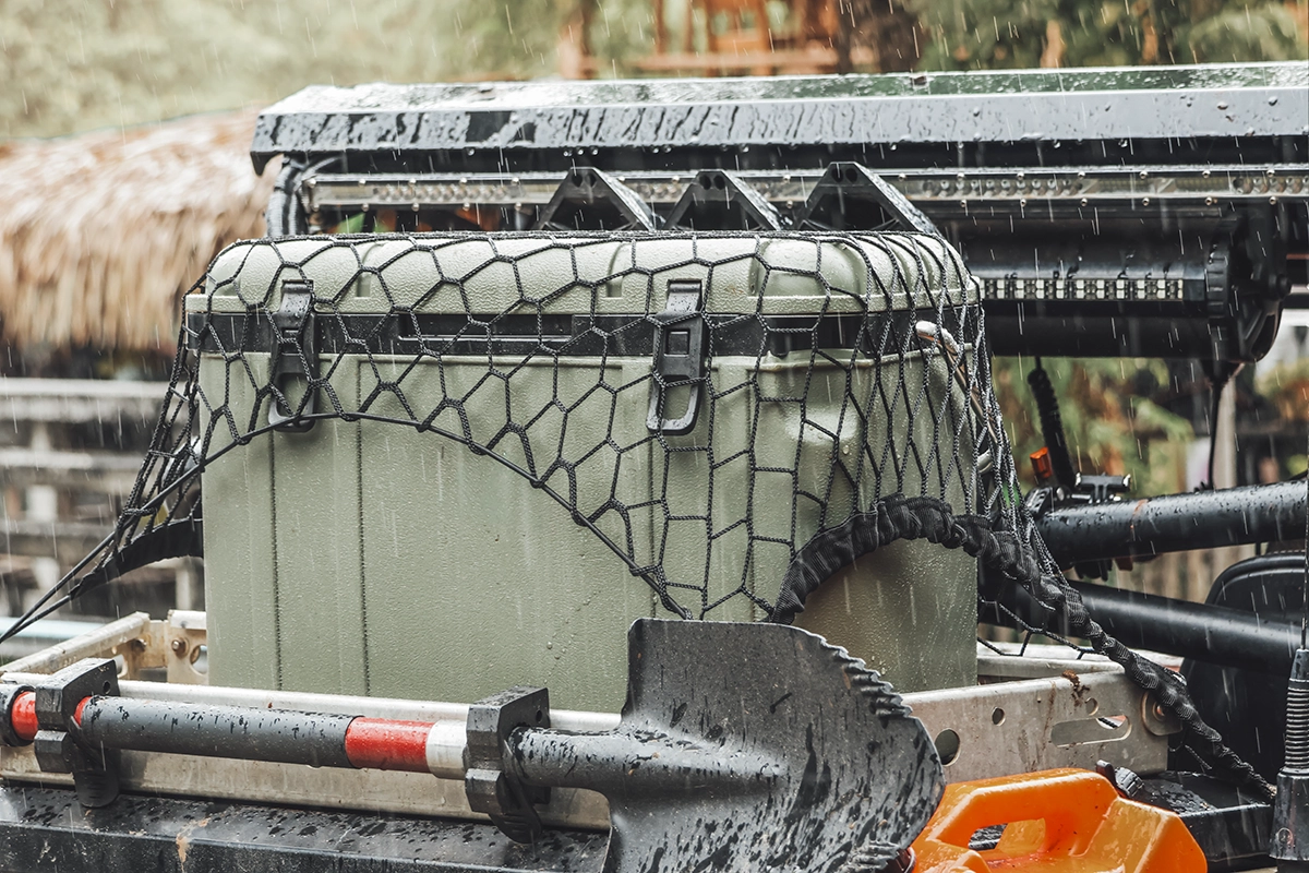 An overlanding vehicle packed with recovery gear, including a shovel, a green cooler, and other off-roading equipment