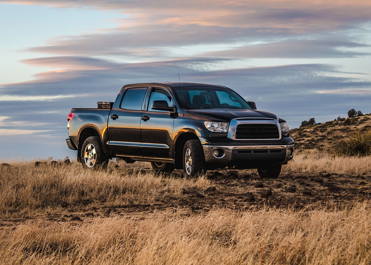 A black pickup truck off-roading in a field of grass