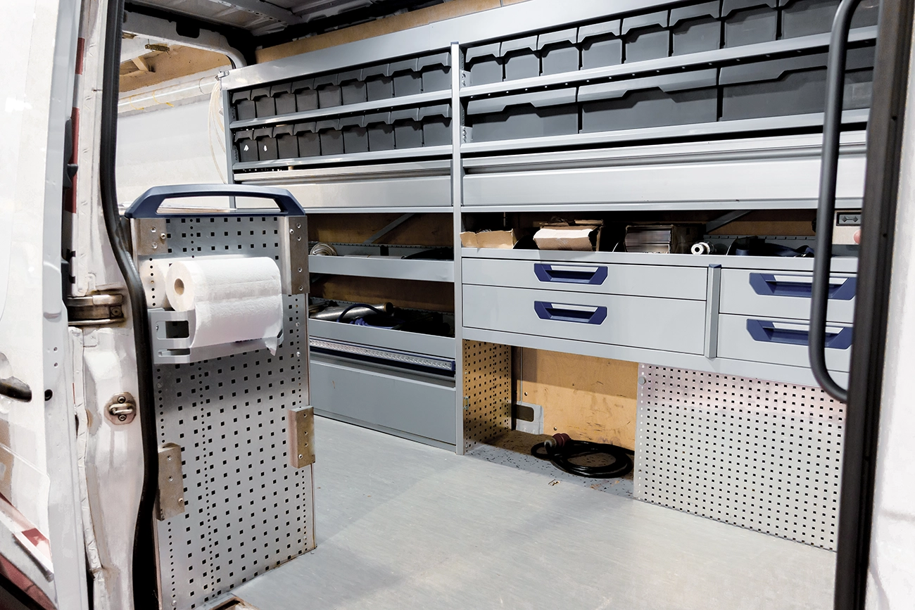 The interior of an organized work van, with shelving units and drawer systems