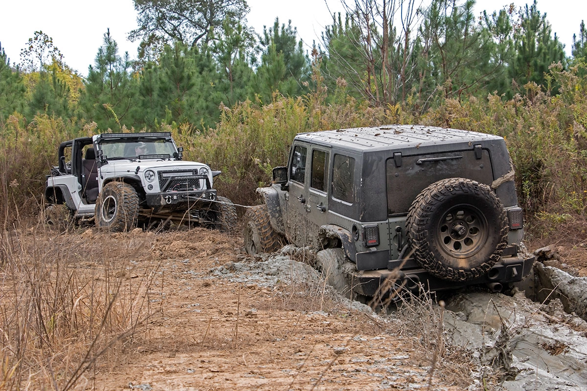 An off-roading vehicle pulling another vehicle out of the mud using a Rough Country winch, showing the concept of overlanding recovery gear