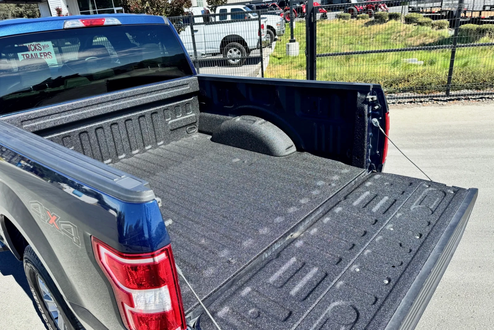 The back of a dark blue pickup truck with Full Metal Jacket spray-on bedliner