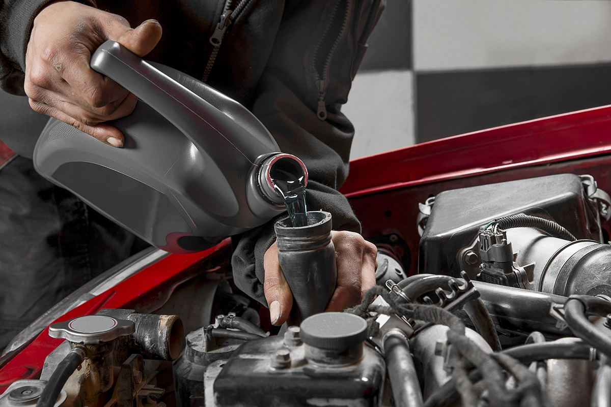 A mechanic replaces coolant or antifreeze for a work truck or van during routine maintenance